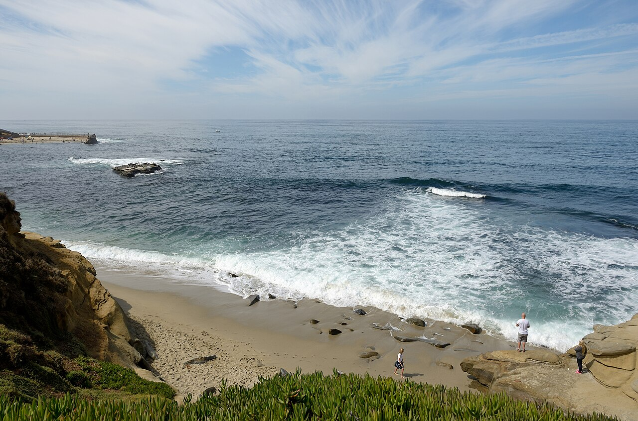 The San Diego coastline near La Jolla, with cliffs, a small sandy cove, and waves rolling in.