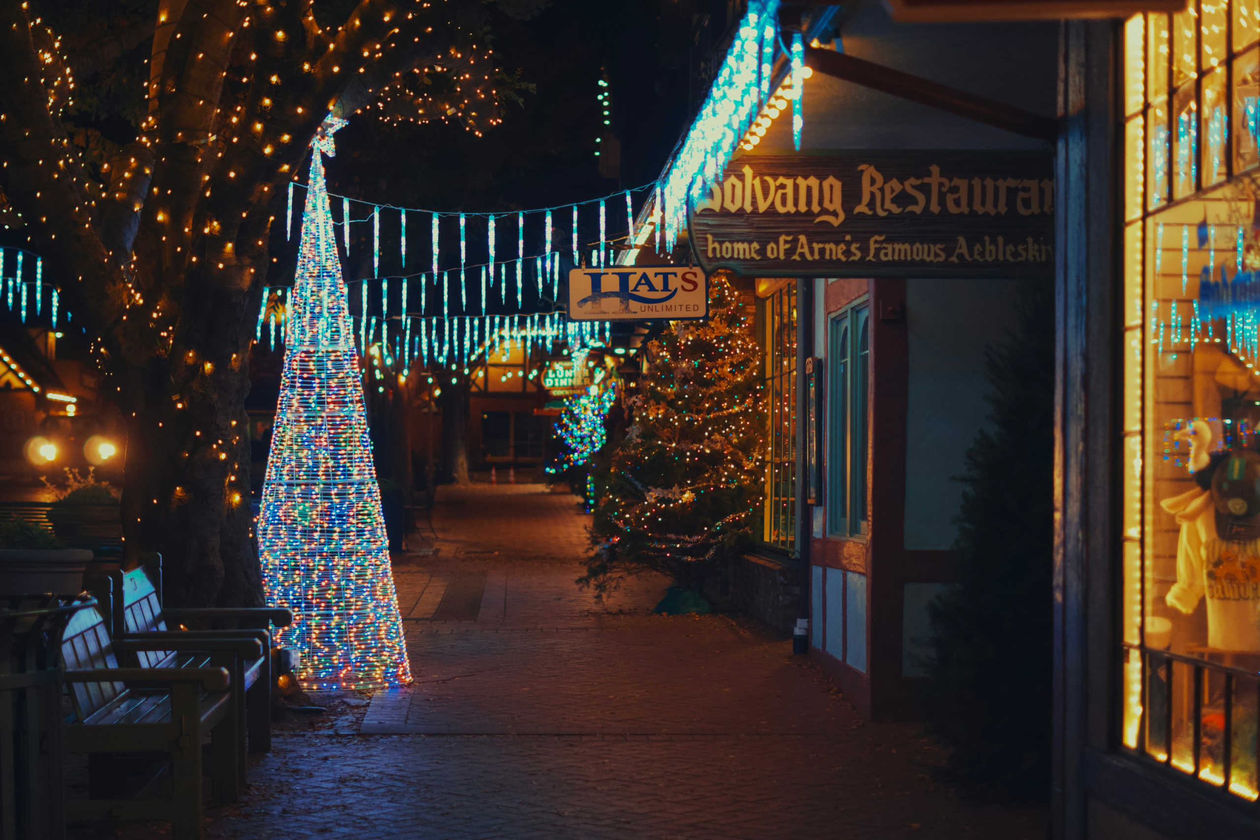A lit Christmas tree and string lights outside Solvang Restaurant on a Solvang, California storefront at night